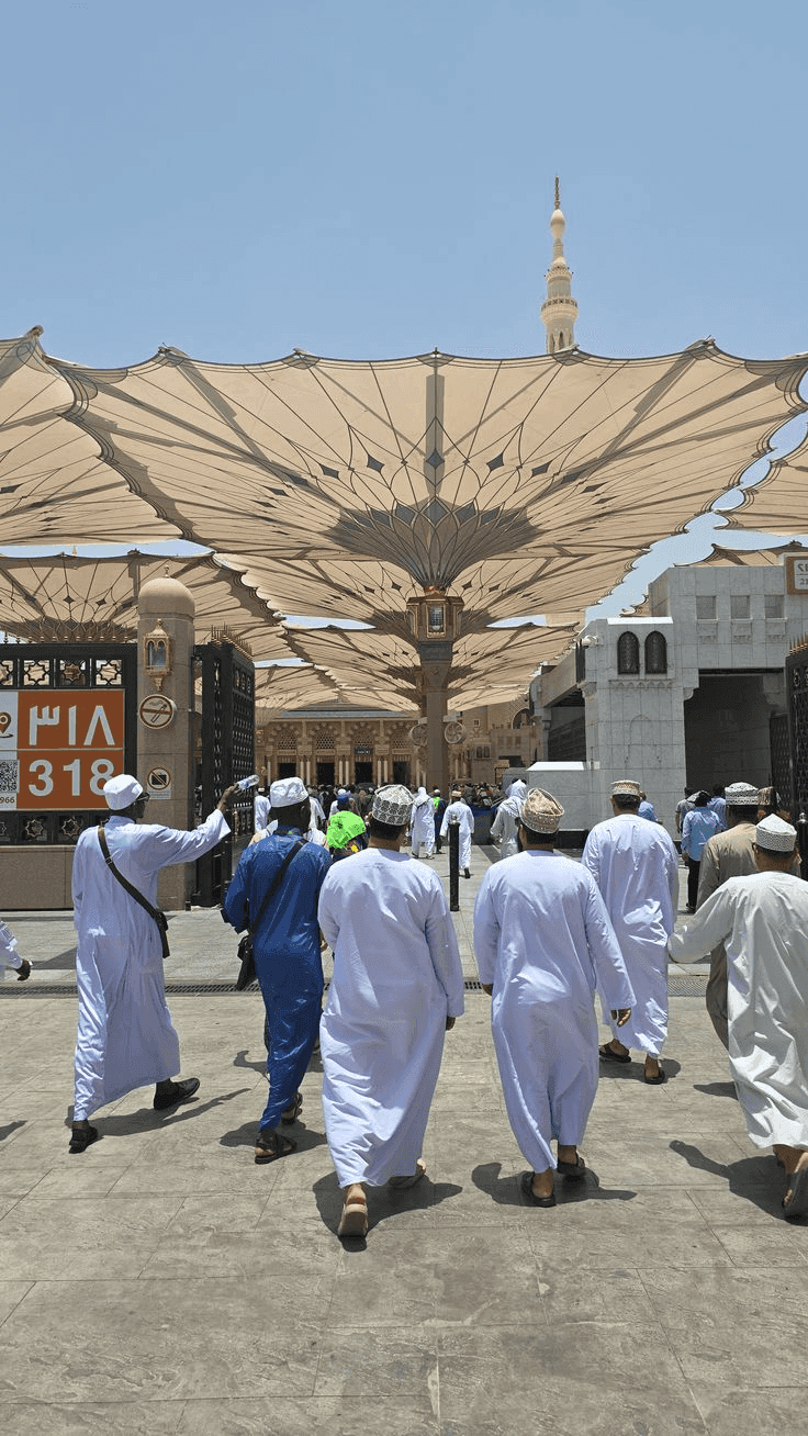 Pilgrims walking towards Gate 318 of the Prophet's Mosque in Madinah, under the courtyard canopies